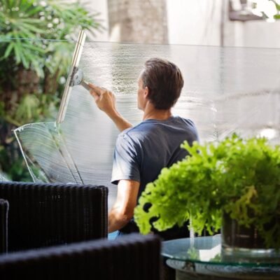 Professional cleaning a large glass window from outside