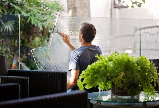 Professional cleaning a large glass window from outside