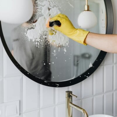 Yellow-gloved hand using squeegee on soapy glass for streak-free windows