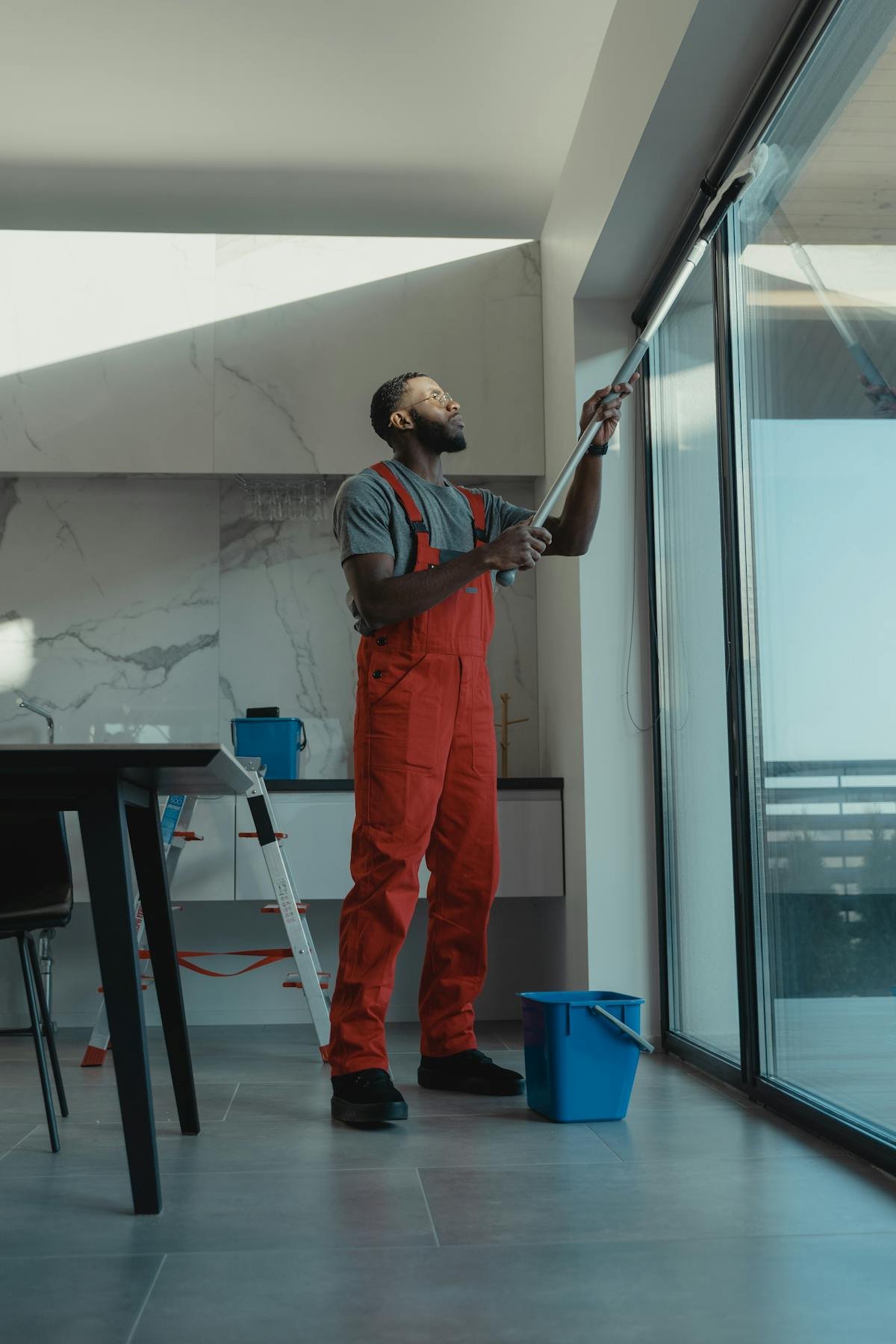 Professional using water-fed pole to clean a large interior window streak-free