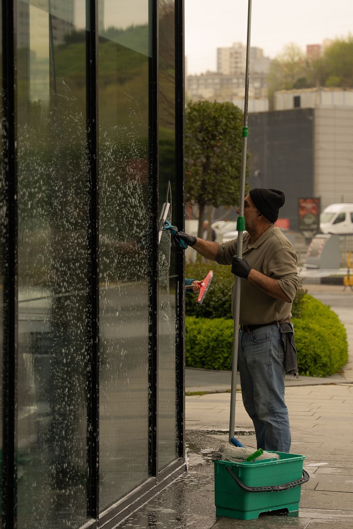 Window cleaning with squeegee on storefront glass — traditional method