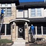 Professional window washing in Chicago suburbs - two Ernest Windows technicians cleaning a stone home