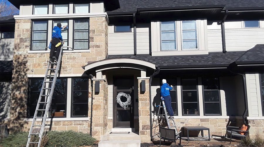 Professional window washing in Chicago suburbs - two Ernest Windows technicians cleaning a stone home