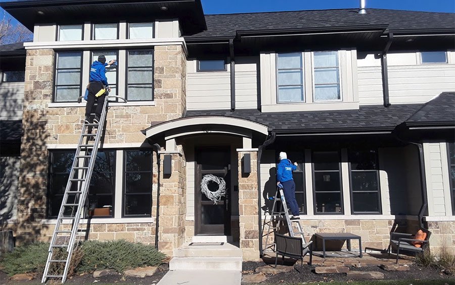 Professional window washing in Chicago suburbs - two Ernest Windows technicians cleaning a stone home