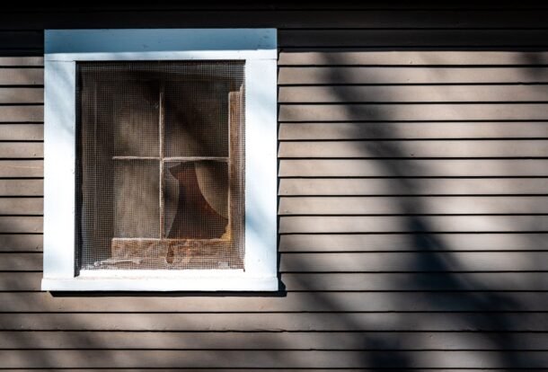 House window covered by an insect screen in afternoon sun
