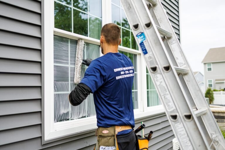 Ernest Windows technician washing a home window with a scrubber